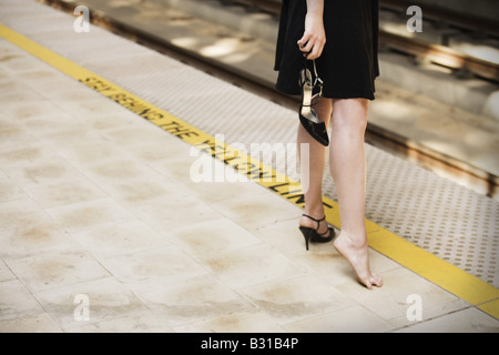 Junge Frau am Bahnsteig mit gebrochenen Schuh Stockfoto