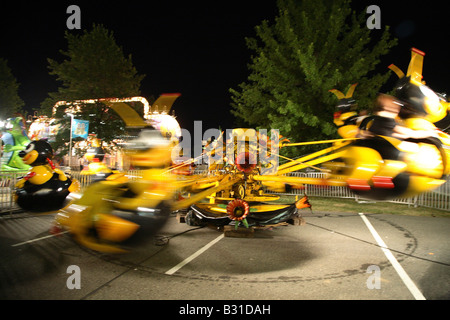 Große gelbe und schwarze Bienen Kinder Messegelände fahren.  Bienen im Kreis nach oben und unten um Blume dreht dekoriert Zentrum Stockfoto