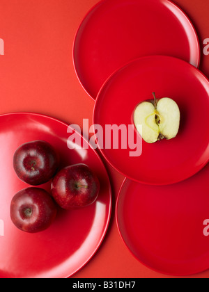rote Äpfel auf roten Platten mit einem halbiert Stockfoto