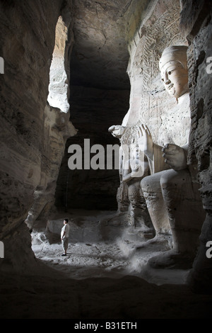 Ein Mann im Schatten einer riesigen Statue in den Yungang buddhistischen Höhlen in der Nähe von Datong, Provinz Shanxi in China. Stockfoto