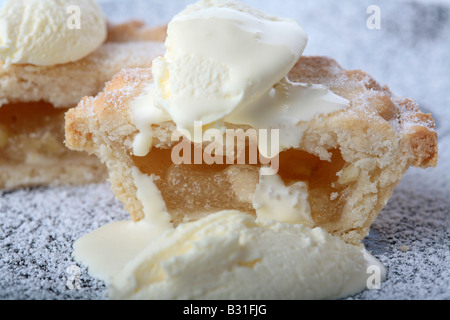 Nahaufnahme einer kleinen Apfelkuchen auf einem Zucker überzogen vergoldet mit geschlagener Sahne und frischen Doppelrahm bedeckt Stockfoto