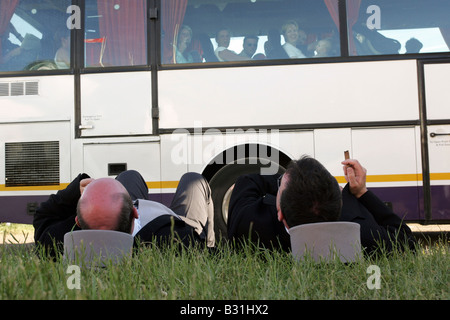 Männer entspannen auf dem Boden während der Pferderennen, Epsom, Großbritannien Stockfoto