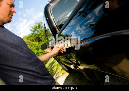 Mann, Geld in Gas-tank Stockfoto