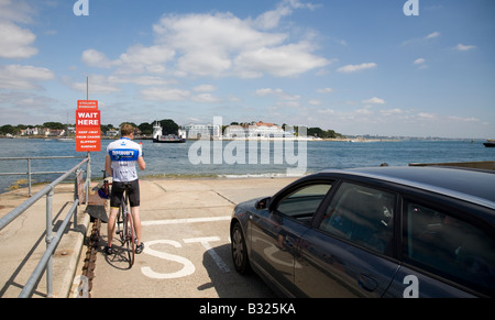 ein männlicher Radfahrer warten mit Fahrzeugen von Studland nach Poole auf die Sandbänke überqueren Fähren England UK Stockfoto