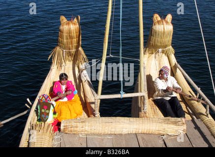 Zwei Mitglieder der Uros Menschen ein Ruderboot am Titicacasee, Peru, Südamerika Stockfoto