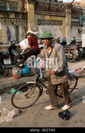 Ein armer Müll Sammler einen grünen Armee Hut schiebt sein Fahrrad in Hanoi Old Quarter Vietnam Stockfoto