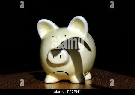 EIN TRAURIG SCHAUEN BRITISH SPARSCHWEIN MIT SCHATTEN EINES HAMMERS SCHWEBT ÜBER ES WIEDER DIE WIRTSCHAFT REZESSION EINSPARUNGEN EINKOMMEN LÖHNE UK. Stockfoto