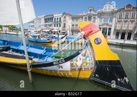 Traditionell bemalten Fischerboote in Aveiro, Portugal mit reich verzierten Gebäuden des alten Hafens im Hintergrund. Stockfoto