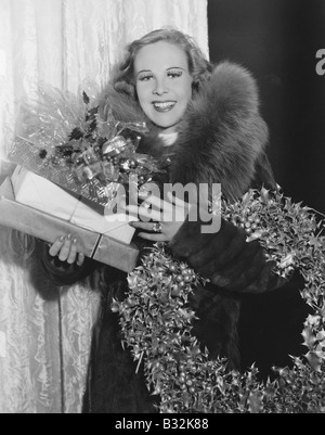 Porträt der Frau mit Adventskranz und Geschenke Stockfoto