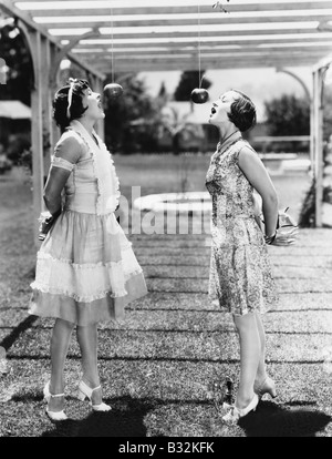 Frauen beißen Äpfel auf Zeichenfolgen an Halloween Stockfoto