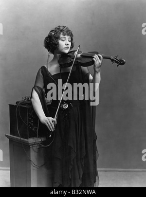 Frau spielt Violine mit Kopfhörer Stockfoto