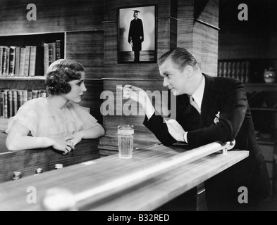 Mann und Frau stehen zusammen in einer Bar Theke und sprechen Stockfoto