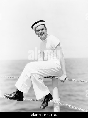 Porträt eines Matrosen am Mast eines Bootes sitzen und Lächeln auf den Lippen Stockfoto