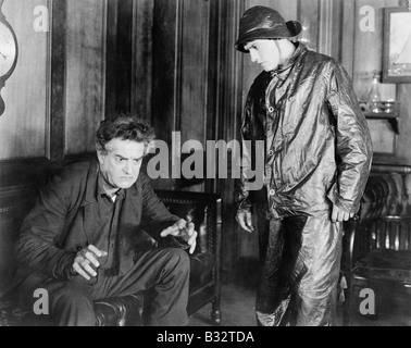 Mann sitzt auf einer Couch, die etwas mit seinen Händen, ein junger Mann vor ihm zu erklären Stockfoto