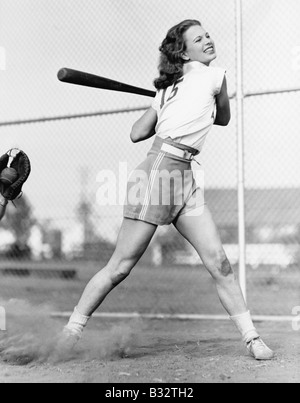 Junge Frau, die einen Baseballschläger geschwungen, in einem Baseballfeld Stockfoto