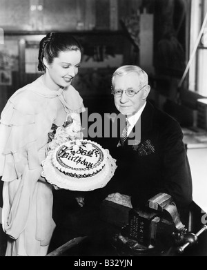 Junge Frau präsentiert einen Geburtstag Kuchen, ein älterer Mann Stockfoto