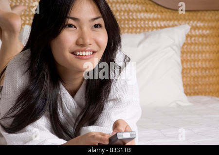 Eine hübsche junge Frau mit Fernbedienung auf Hotelbett - Nahaufnahme Stockfoto