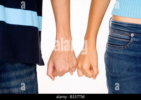 Zwei junge Erwachsene, die mit jeweils anderen kleinen Finger Stockfoto