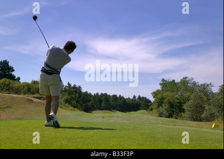 Schuss von einem männlichen Golfer Abschlag mit dem Ball in der Luft an einem sonnigen Tag leichte Bewegungsunschärfe auf den Verein Stockfoto