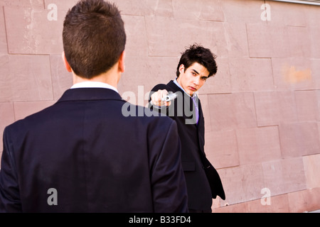 Gut gekleideter Mann, mit dem Ziel, zum anderen mit einer Pistole Stockfoto