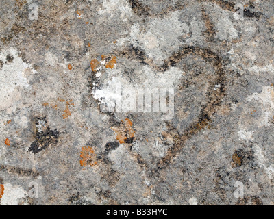ein altes Herz geschnitzt in Steinmauer in Sonne Stockfoto