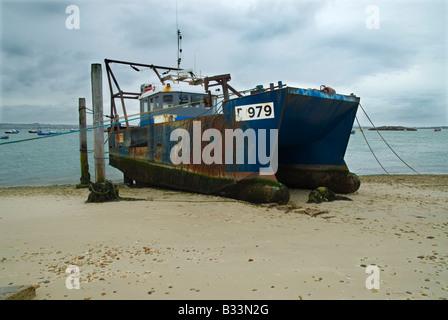 Steuerbordseite Blick auf eine alte blaue Trawler bei Ebbe an einem Sandstrand. Stockfoto