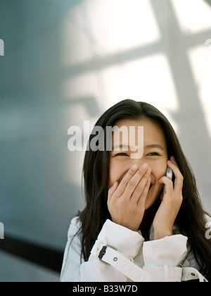 Eine junge chinesische Geschäftsfrau mit ihrem Handy PDA in der Stadt Stockfoto