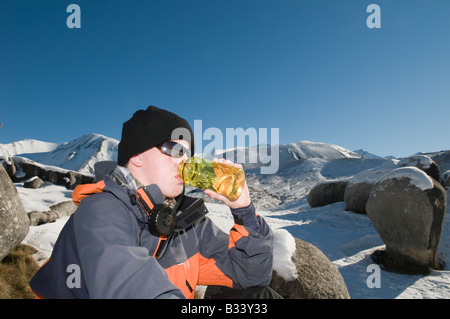 Ein müde Winterwanderer Getränke aus seiner Flasche Wasser in das Hochland von Canterbury Stockfoto