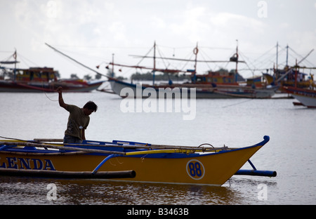 Ein Filipino beginnt seine Bangka-Boot in der Mansalay Bucht, Oriental Mindoro, Philippinen. Stockfoto