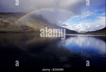 Regenbogen über See in der Nähe von Almhütte Olavsbu im Tal Raudalen der Landschaft Gebirge Jotunheimen, Norwegen Stockfoto