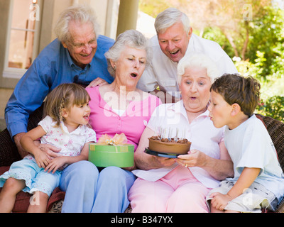 Großeltern und Enkelkinder auf Terrasse mit Kuchen und Geschenk lächelnd Stockfoto