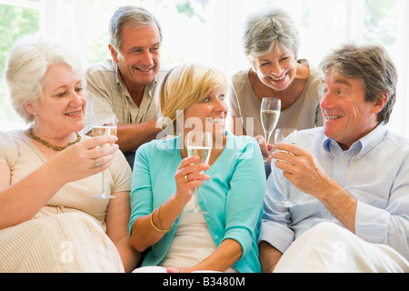 Fünf Freunde im Wohnzimmer trinken Champagner und lächelnd Stockfoto
