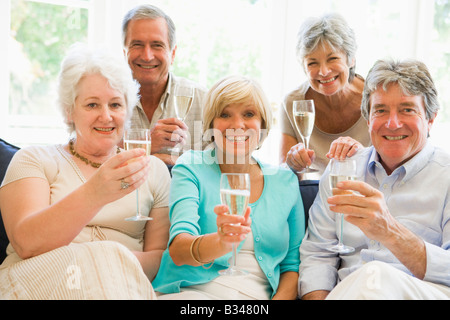 Fünf Freunde im Wohnzimmer trinken Champagner und lächelnd Stockfoto