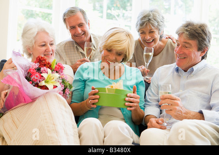 Fünf Freunde mit Champagner und Geschenke im Wohnzimmer lächelnd Stockfoto