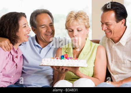 Zwei Paare im Wohnzimmer lächelnd mit Frau Ausblasen der Kerzen auf Kuchen Stockfoto