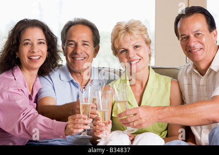 Zwei Paare im Wohnzimmer trinken Champagner und lächelnd Stockfoto