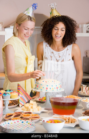 Zwei Frauen auf Party setzen Kerzen im Kuchen lächelnd Stockfoto