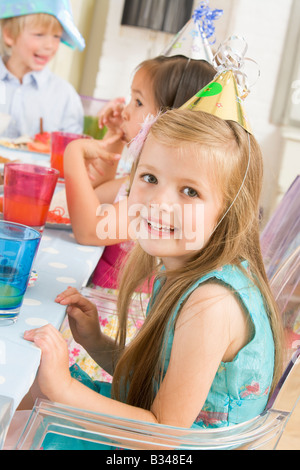 Junges Mädchen auf Party mit Lächeln auf den Lippen Essen am Tisch sitzen Stockfoto