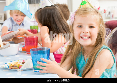 Junges Mädchen auf Party mit Lächeln auf den Lippen Essen am Tisch sitzen Stockfoto