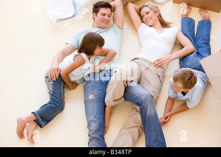 Familie im neuen Hause lächelnd am Boden durch offene Boxen liegend Stockfoto