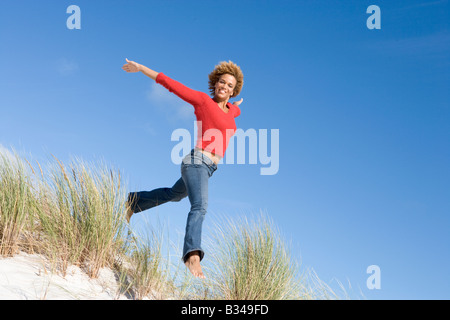 Junge Frau springen auf einem Sandhügel Stockfoto