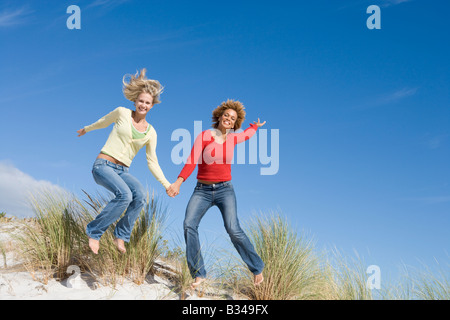 Junge Frau springen auf einem Sandhügel Stockfoto