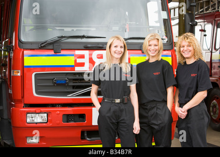 Drei Feuerwehrleute stehen vor Feuerwehrauto Stockfoto