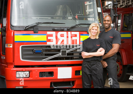 Zwei Feuerwehrleute stehen vor Feuerwehrauto Stockfoto