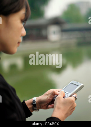 Eine chinesische Geschäftsfrau mit ihrem Mobiltelefon mit chinesischer Architektur im Hintergrund Stockfoto