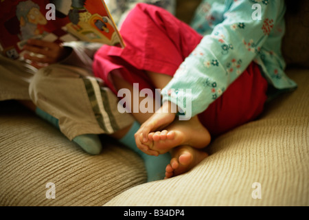 Jungen im Alter von sechs Jahren liest eine Geschichte um seine kleine Schwester im Alter von fünf Jahren Stockfoto