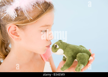 Junges Mädchen in Prinzessin Kostüm Plüsch Frosch küssen Stockfoto