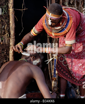 Kenya, Samburu District Maralal. Samburu Mutter rasiert ihres Sohnes Kopf vor ihrem Haus am Tag bevor er beschnitten ist. ASD Stockfoto