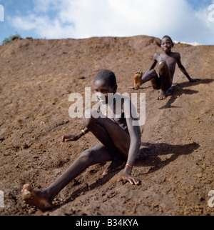 Kenya, Samburu District, Lodungokwe. Junge Samburu Jungs Vergnügen sich auf einem Erdrutsch. Stockfoto