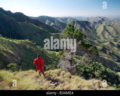 Kenya, Samburu District, Losiolo. Ein Samburu Krieger blickt auf eine weite des unwirtlichen Land aus den östlichen Steilhang des afrikanischen Great Rift Valley am Losiolo, nördlich von Maralal. Von 8.000 Fuß stürzt das Land Weg 3.000 Fuß in zerklüfteten Tälern und einer weiten Ebene, die Domäne der nomadisierenden Viehzüchtern, stieg wieder 75 Meilen entfernt. Die Aussicht auf Losiolo sind die spektakulärsten in Kenia von den größten, längsten und auffälligste Merkmal seiner Art auf der Erde. Stockfoto